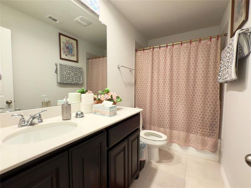 Full bath with light tile patterned flooring, vanity, and shower / bathtub combination with curtain Full bath with light tile patterned flooring, vanity, and shower / bathtub combination with curtain