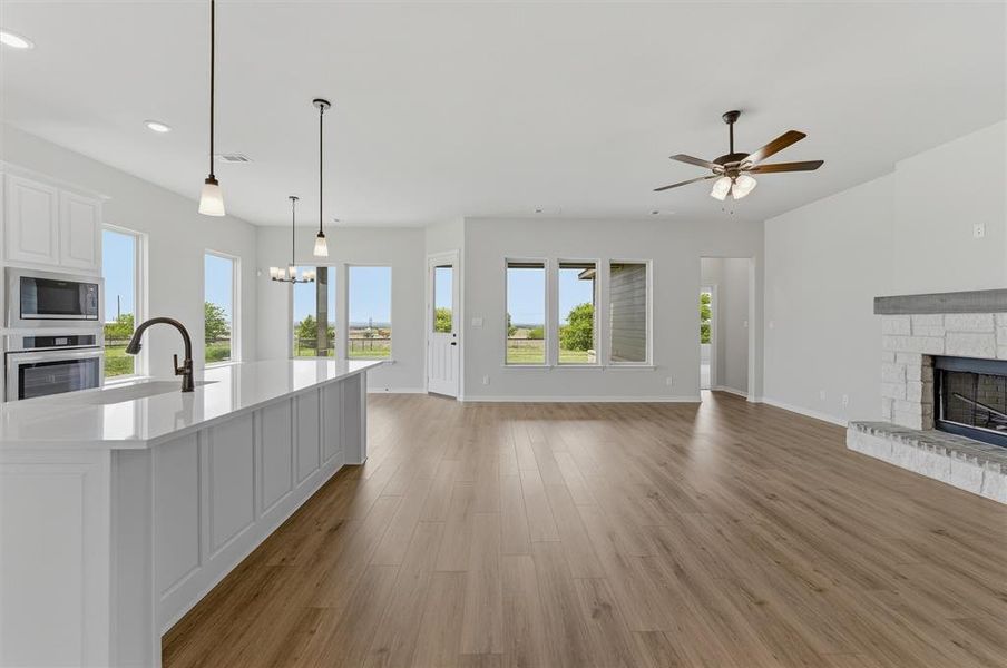 Unfurnished living room featuring a fireplace, dark wood-type flooring, hanging lights, and a ceiling fan Unfurnished living room featuring a fireplace, dark wood-type flooring, hanging lights, and a ceiling fan
