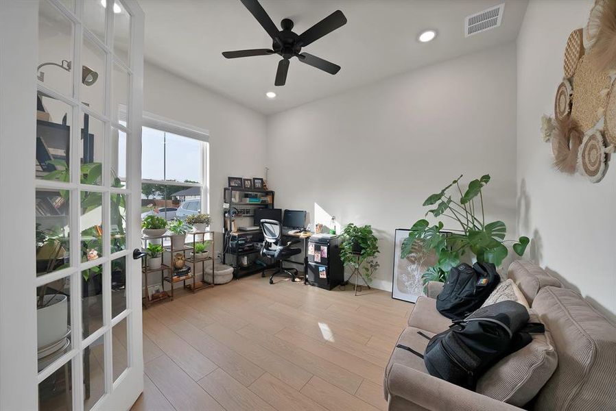 Bright room featuring French doors with glass panes, wood-finish flooring, a large window, a ceiling fan, and recessed lighting Bright room featuring French doors with glass panes, wood-finish flooring, a large window, a ceiling fan, and recessed lighting