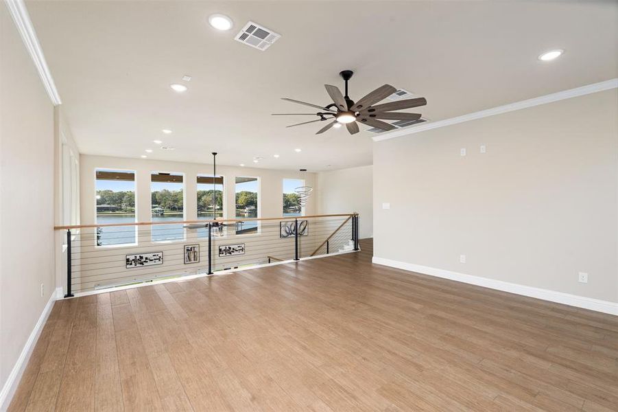 Spare room featuring crown molding, light hardwood / wood-style flooring, a healthy amount of sunlight, and ceiling fan