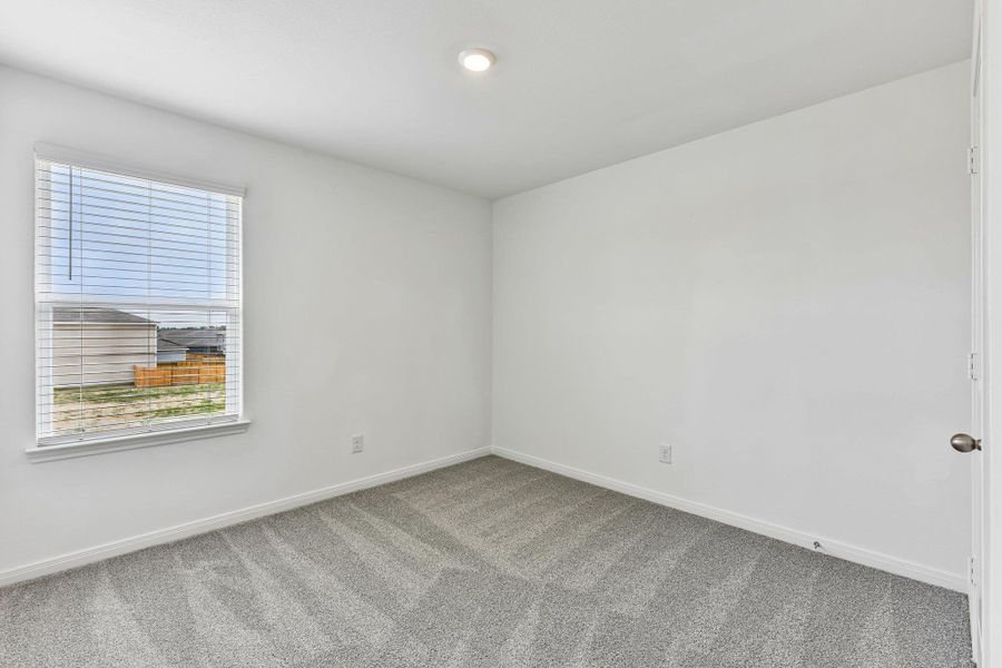 Neutral interior featuring light gray patterned carpeting, white painted walls, and a single recessed ceiling light fixture