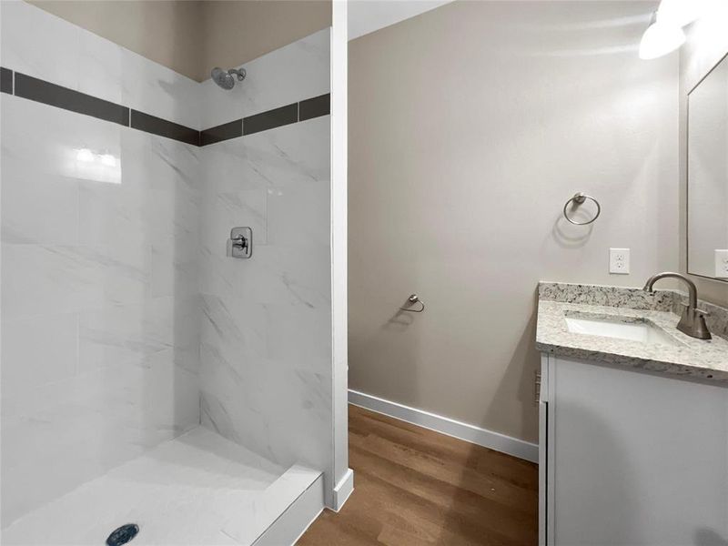 Full bathroom featuring vanity, a marble finish shower, and wood finished floors