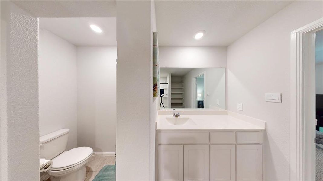 Contemporary vanity with white cabinetry, a single basin sink, and a large wall-mounted mirror