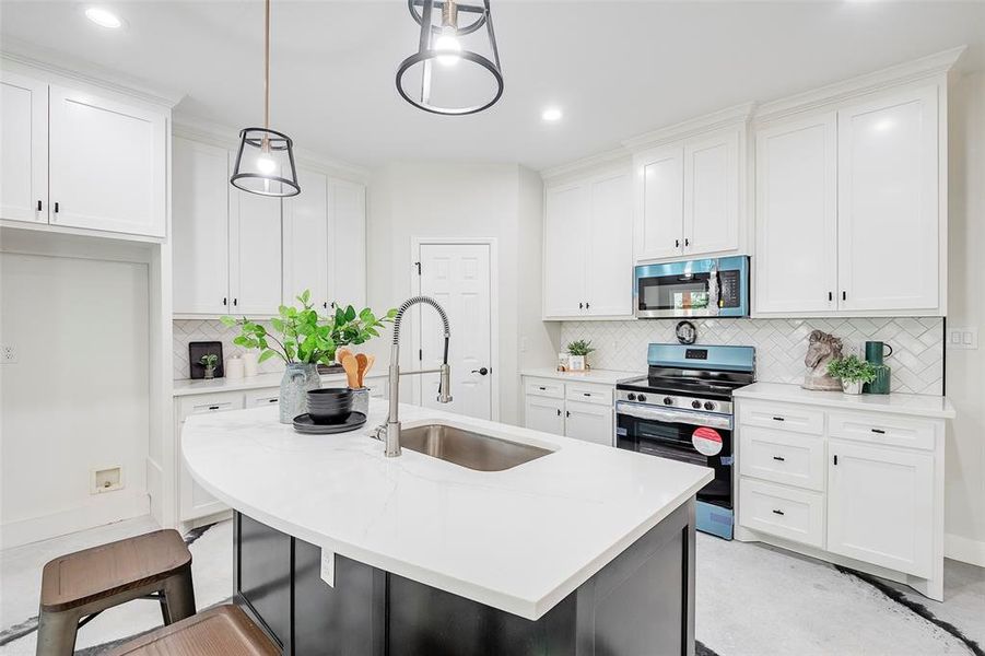 Kitchen featuring white cabinetry, tasteful backsplash, a kitchen island with sink, appliances with stainless steel finishes, and sink