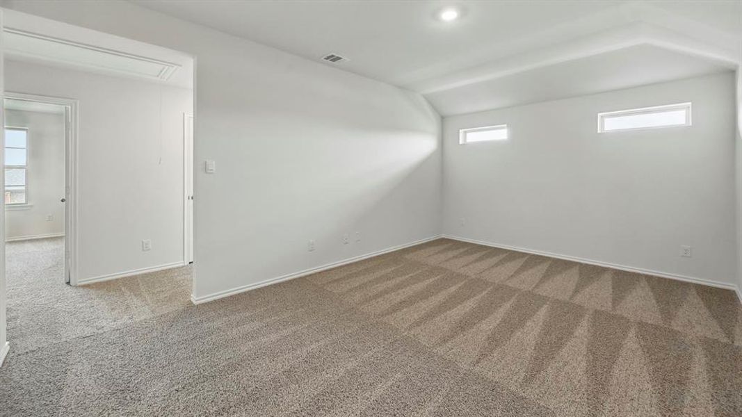 Carpeted spare room featuring attic access and baseboards