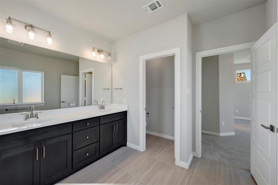 Bathroom with double vanity and light tile patterned floors