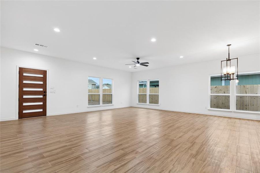 Unfurnished living room with light hardwood / wood-style floors and ceiling fan with notable chandelier