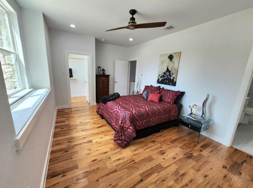 Bedroom featuring connected bathroom, ceiling fan, and light wood-type flooring