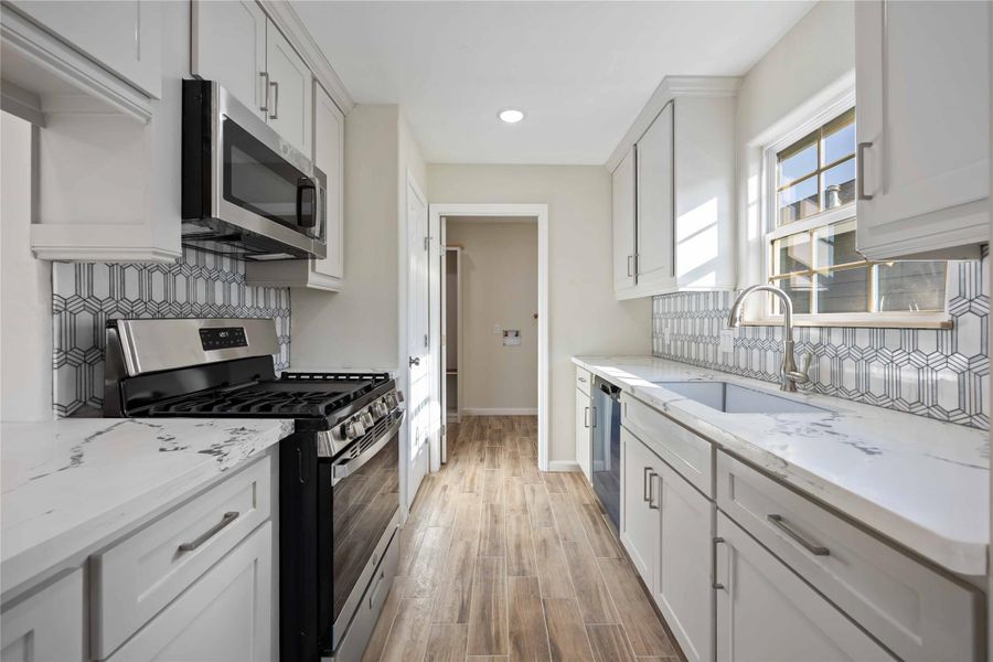 Another view of the kitchen highlighting the ample counter space and clean, modern finishes.