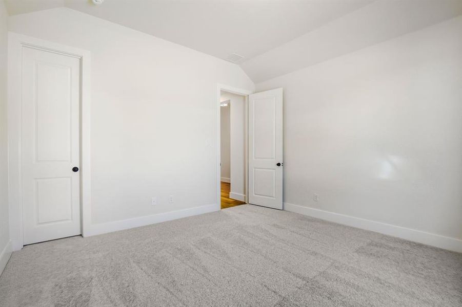Unfurnished room with vaulted ceiling and light colored carpet