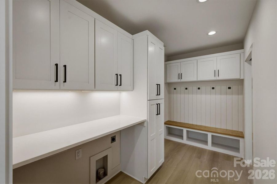 The laundry room is elevated by having a quartz counter top with space for a washer/dryer underneath. The laundry area is located between the walk-in pantry and the door that leads into the 2 car garage. There is a dropzone "cubbie" area beside the door to the garage with a bench, hooks for coats and space for shoes. The laundry room is elevated by having a quartz counter top with space for a washer/dryer underneath. The laundry area is located between the walk-in pantry and the door that leads into the 2 car garage. There is a dropzone "cubbie" area beside the door to the garage with a bench, hooks for coats and space for shoes.