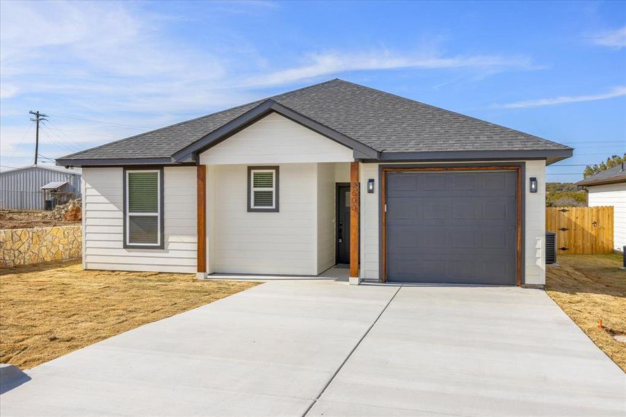 Ranch-style home featuring a garage and central AC unit