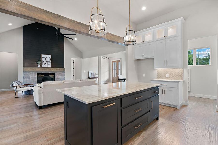 Kitchen featuring white cabinetry, beam ceiling, a kitchen island, and a fireplace