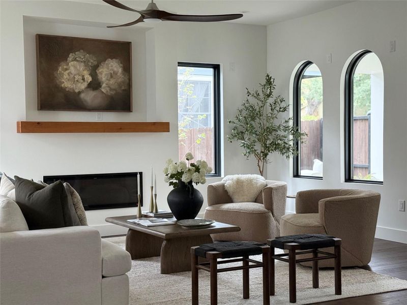 Living area featuring a wall-mounted linear fireplace, natural wood mantel, and dark wood-finish flooring
