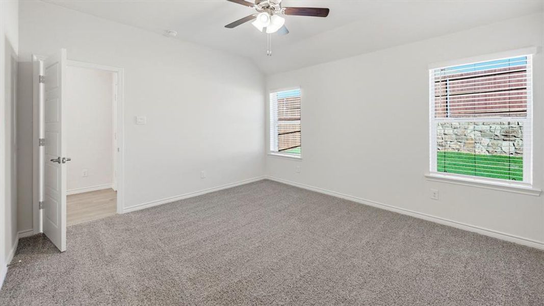 Spare room featuring light colored carpet, lofted ceiling, and a ceiling fan
