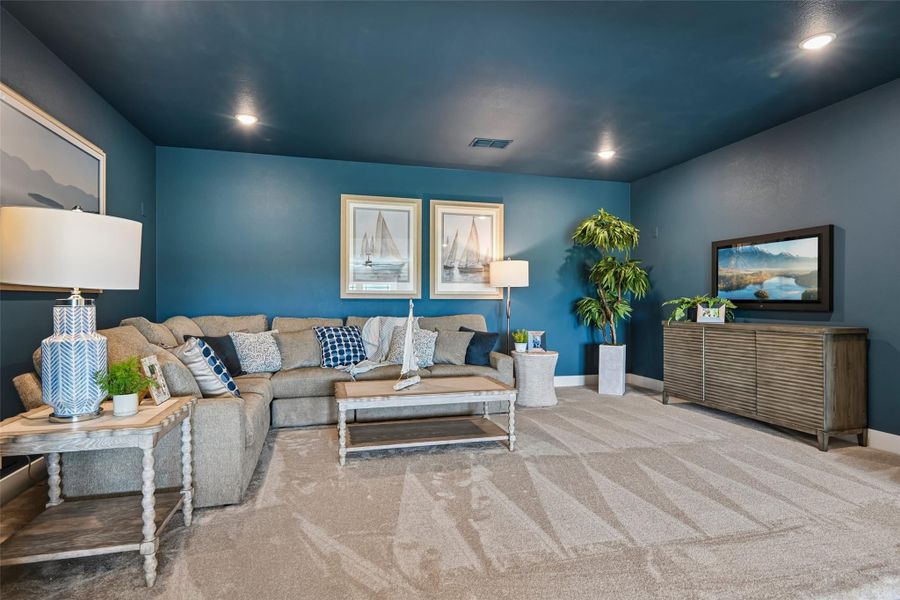 Living room with blue walls, gray sectional sofa, carpet flooring, and wall-mounted TV Living room with blue walls, gray sectional sofa, carpet flooring, and wall-mounted TV