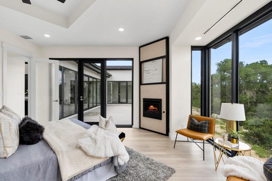 Bedroom featuring a large fireplace, light wood-style flooring, recessed lighting, multiple windows, and access to outside
