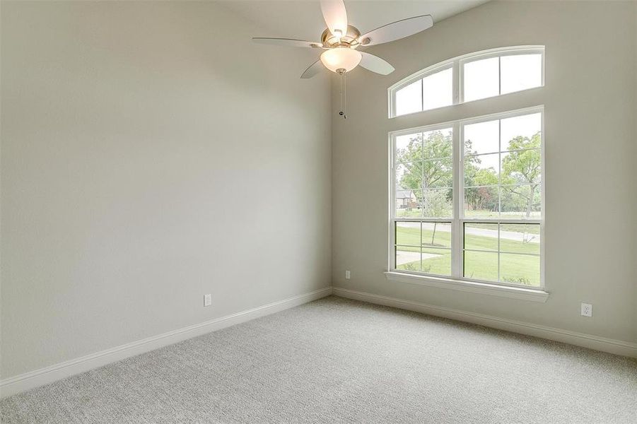 Unfurnished room with light colored carpet, plenty of natural light, and ceiling fan