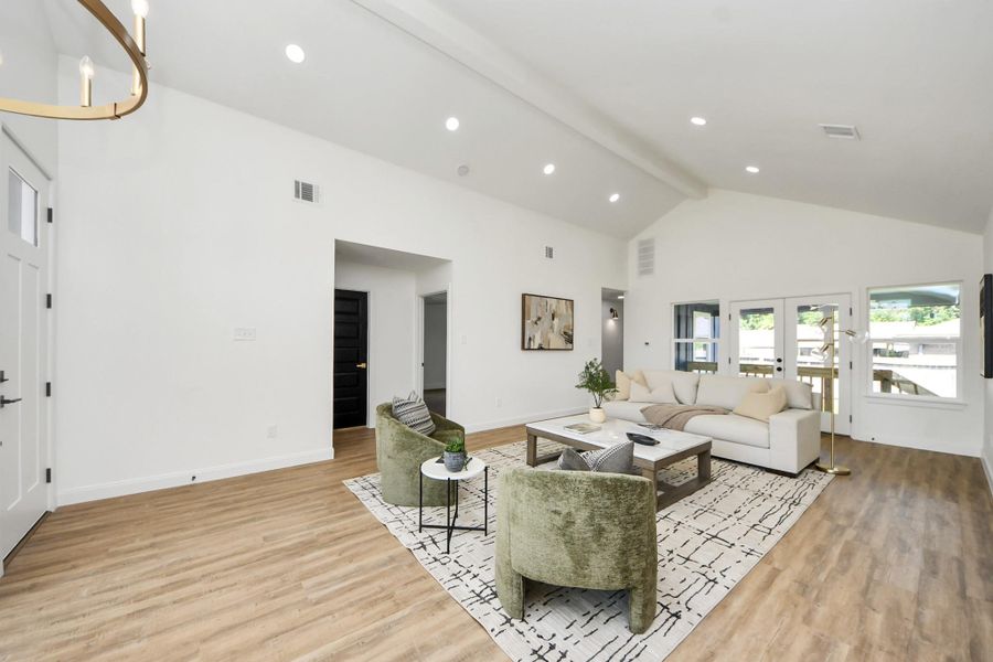An airy, open living space where vaulted ceilings and natural light set a calming tone. Light wood floors and thoughtfully styled seating invite you to unwind, while the clean, modern layout makes the room feel both spacious and intimate.