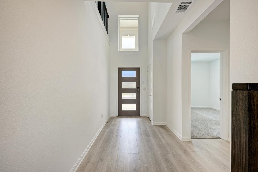 Enter into a soaring foyer with light wood-look flooring and a contemporary front door.