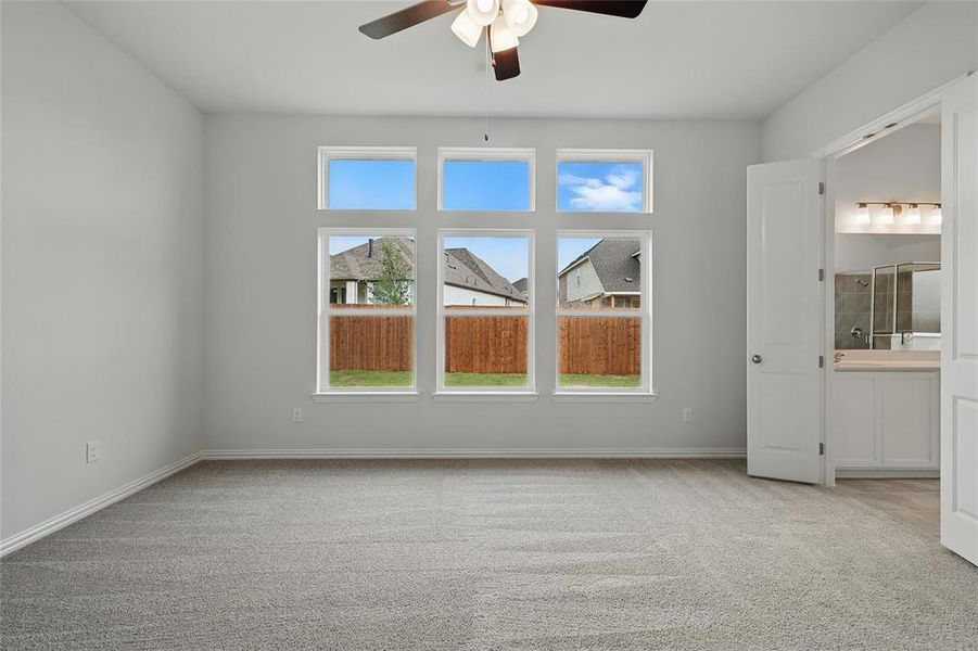 Unfurnished bedroom featuring light carpet, ceiling fan, and ensuite bath