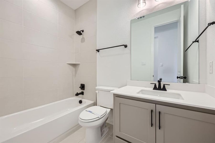 Full bathroom featuring vanity, tiled shower / bath combo, and toilet