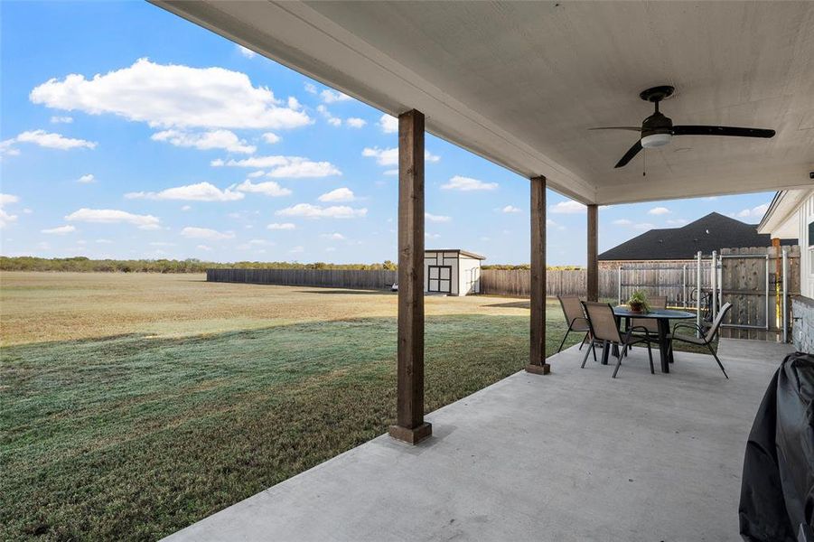 Fenced backyard featuring a patio area, ceiling fan, a storage unit, and outdoor dining area