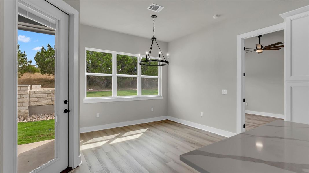 Unfurnished dining area featuring healthy amount of natural light, a ceiling fan, suspended lighting, and light wood finished floors