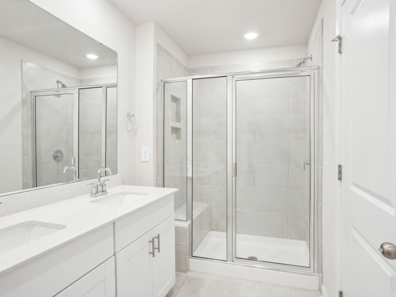 The primary bathroom boasts a dual-sink vanity and spacious walk-in shower.