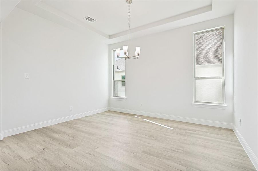 Empty room featuring light hardwood / wood-style floors, a wealth of natural light, and a chandelier