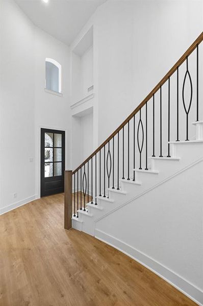Foyer entrance featuring stairway, light wood-style flooring, and a high ceiling Foyer entrance featuring stairway, light wood-style flooring, and a high ceiling