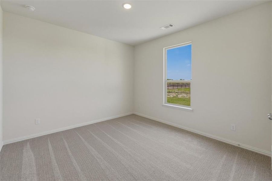 Spacious room featuring neutral carpeting, recessed ceiling lighting, a single window, and light-toned walls Spacious room featuring neutral carpeting, recessed ceiling lighting, a single window, and light-toned walls