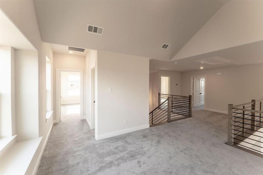 Carpeted empty room featuring lofted ceiling