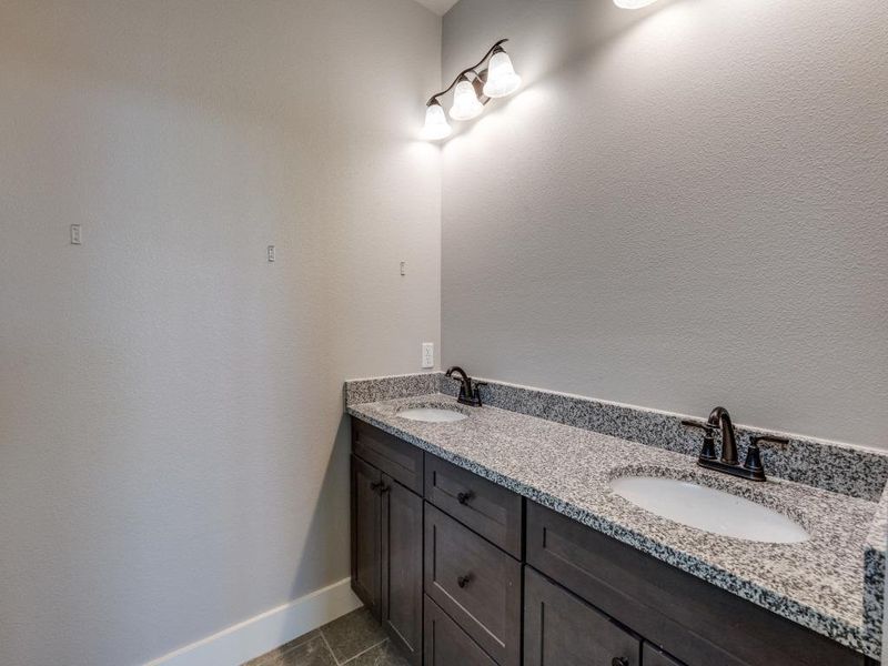 Bathroom with double vanity, tile patterned flooring, baseboards, and a sink