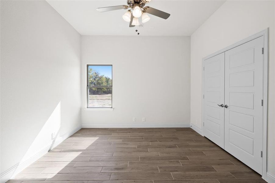 Unfurnished bedroom with wood tiled floors, a closet, and a ceiling fan Unfurnished bedroom with wood tiled floors, a closet, and a ceiling fan