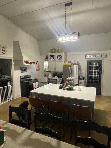 Kitchen with white cabinets, refrigerator, dishwashing machine, a kitchen bar, and range