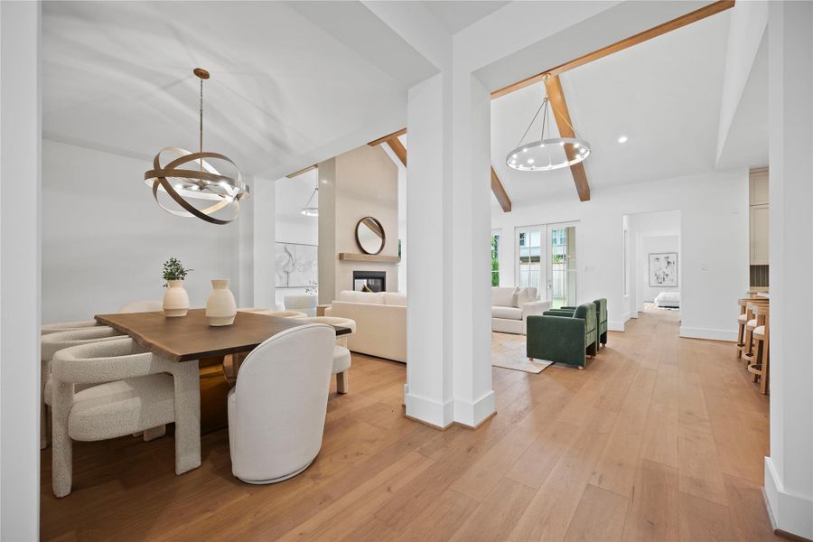 This photo showcases a spacious open-concept living area with elegant light fixtures, large windows, and exposed wooden beams. The room features engineered white oak floors and a modern fireplace, creating a warm and inviting atmosphere. This photo showcases a spacious open-concept living area with elegant light fixtures, large windows, and exposed wooden beams. The room features engineered white oak floors and a modern fireplace, creating a warm and inviting atmosphere.