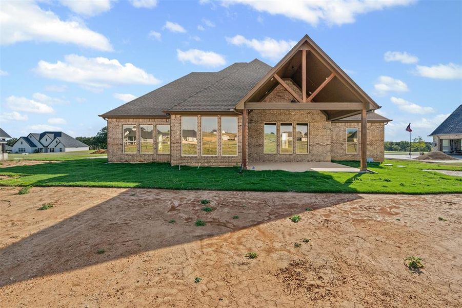 Rear view of property with a patio, brick siding, a yard, and a shingled roof