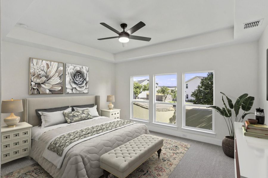 Carpeted bedroom featuring a tray ceiling, contemporary ceiling fan, and three large windows providing ample natural light Carpeted bedroom featuring a tray ceiling, contemporary ceiling fan, and three large windows providing ample natural light