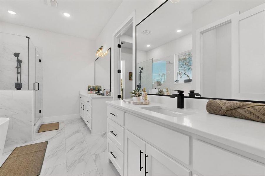 Bathroom with a marble finish shower, two vanities, a soaking tub, light marble finish flooring, and recessed lighting