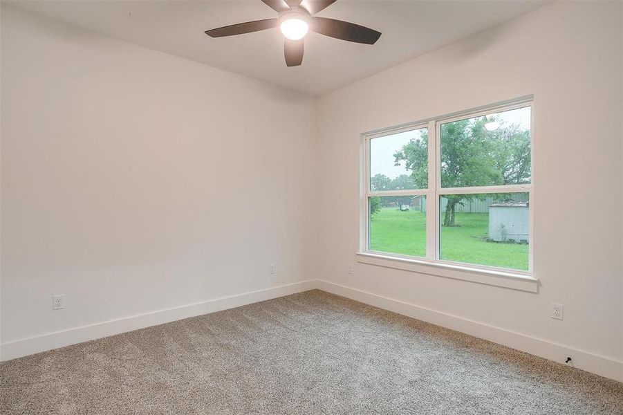 Carpeted spare room with baseboards and ceiling fan