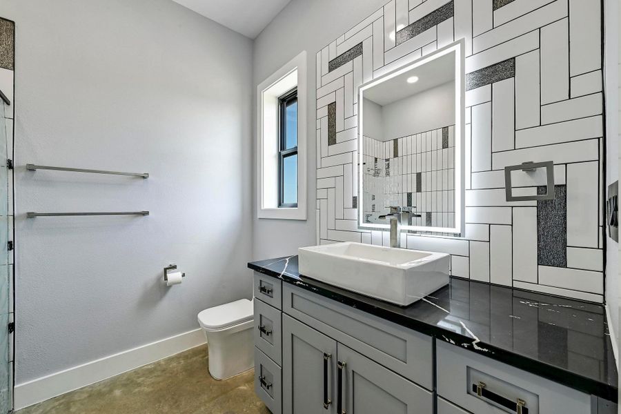 The guest ensuite bathroom is also adorned with designer finishes, a lit mirror, and unique modern backsplash. The guest ensuite bathroom is also adorned with designer finishes, a lit mirror, and unique modern backsplash.