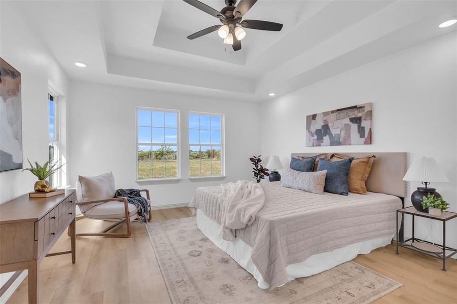 Bedroom featuring light wood-style floors, ceiling fan, recessed lighting, and a tray ceiling Bedroom featuring light wood-style floors, ceiling fan, recessed lighting, and a tray ceiling