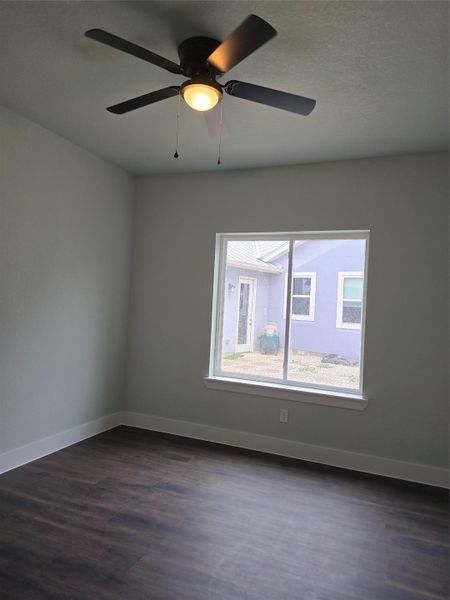Spare room featuring dark wood-style flooring and a ceiling fan