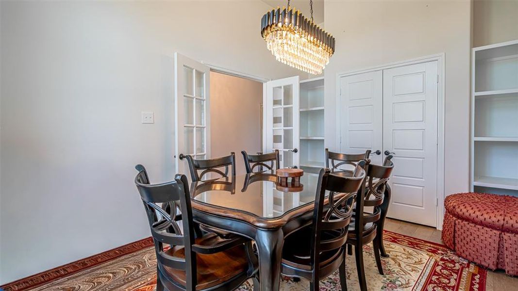 Dining area with a crystal chandelier, wood-finish flooring, and built-in shelving