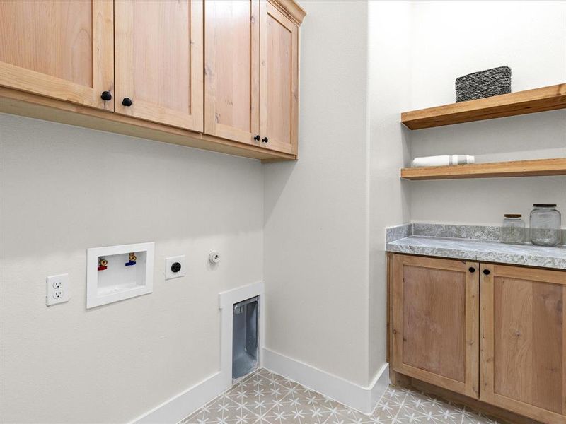 Laundry area with gas dryer hookup, cabinet space, washer hookup, and light tile patterned flooring