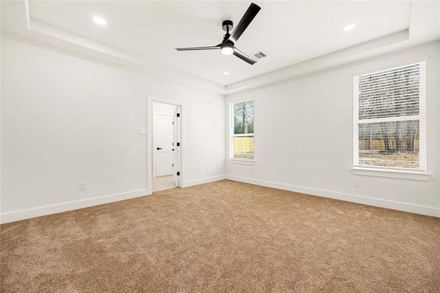 Spacious walk-in closet with ample shelving and hanging space, featuring neutral carpeting and a bright, white finish for a clean look.