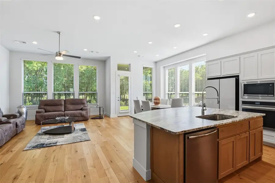 Open-concept living space featuring wood-finish flooring, recessed lighting, and large windows Open-concept living space featuring wood-finish flooring, recessed lighting, and large windows