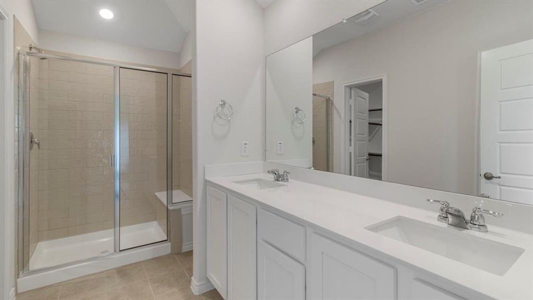 Full bath featuring a shower stall, double vanity, light tile patterned flooring, and a walk in closet Full bath featuring a shower stall, double vanity, light tile patterned flooring, and a walk in closet