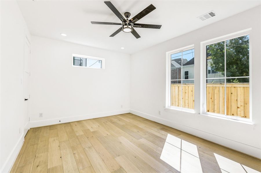 A bright and serene view of the room highlights its clean architectural lines and modern ceiling fan with integrated lighting. The clerestory window allows natural light while preserving privacy, and the neutral designer paint palette ensures a seamless flow with the rest of the home’s moderninterior.